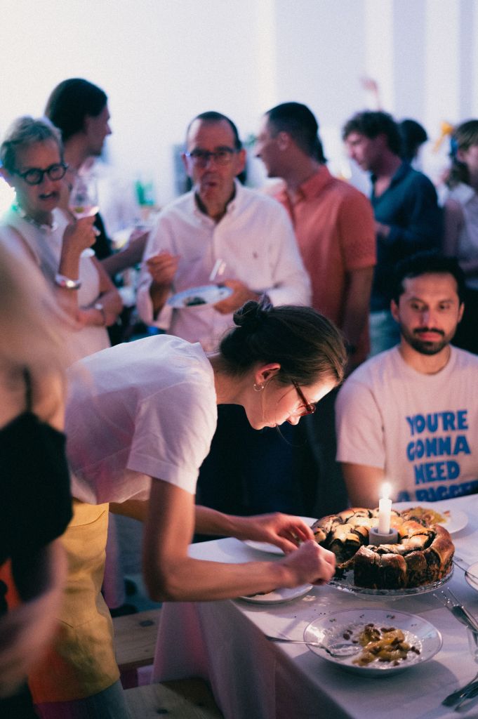 Hospitality staff wearing a yellow apron preparing a cake during a restaurant service event