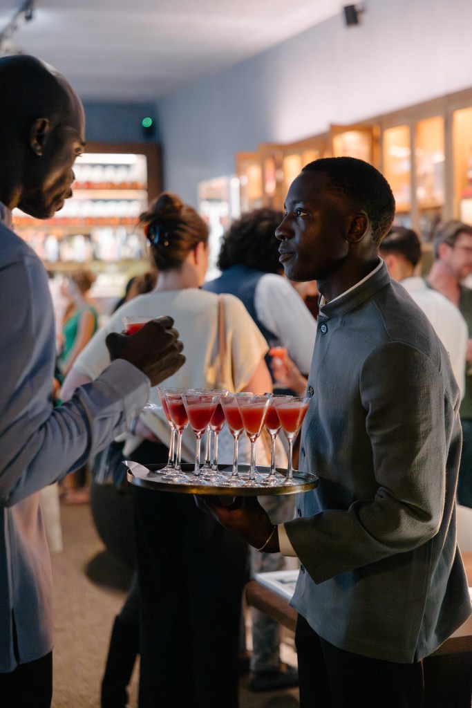 Hospitality staff with jackets serving cocktails on a tray during a restaurant event, professional service moment